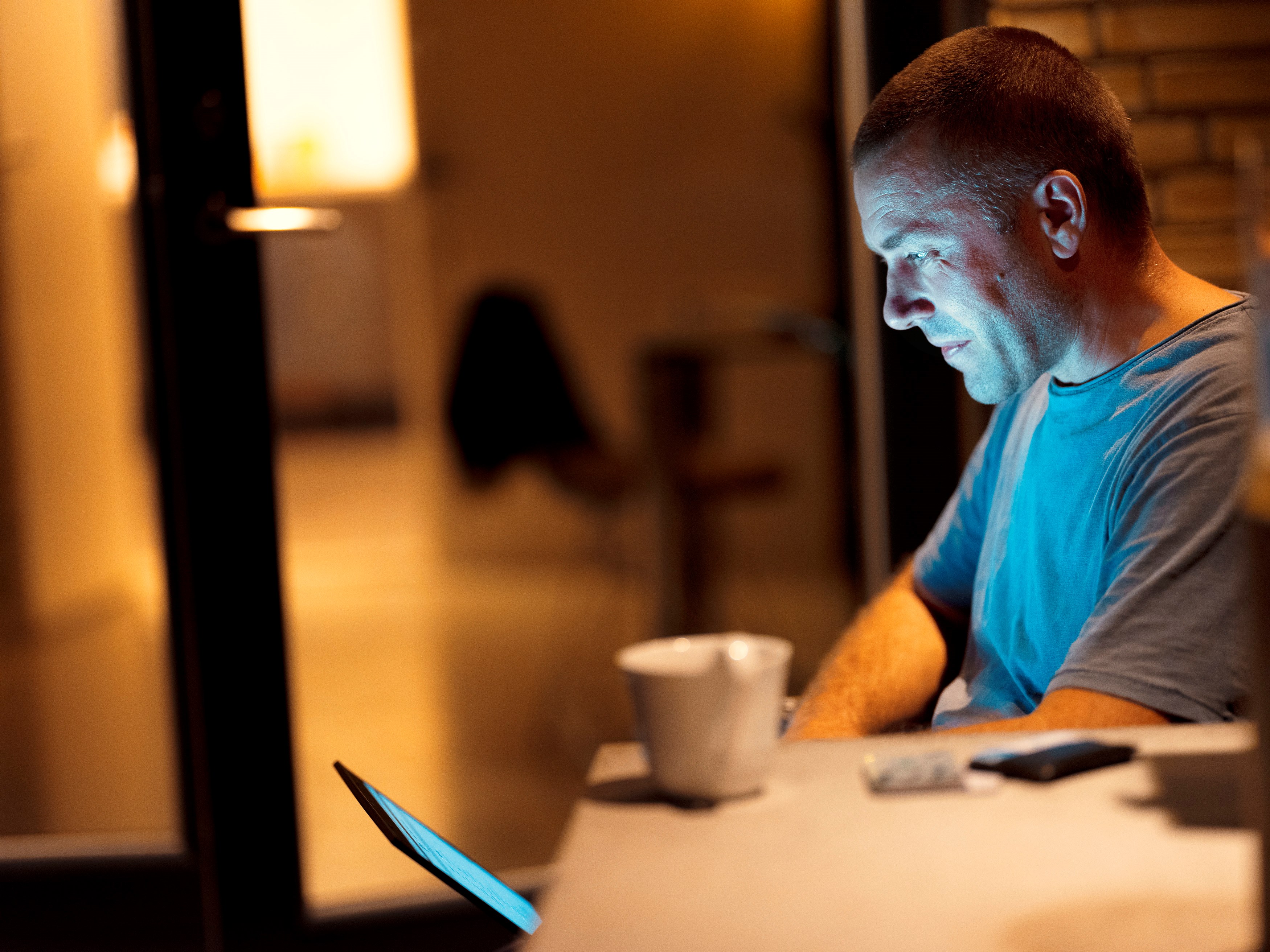 En mand kigger på sin computer og pensionsopsparing i aftenlysets skær